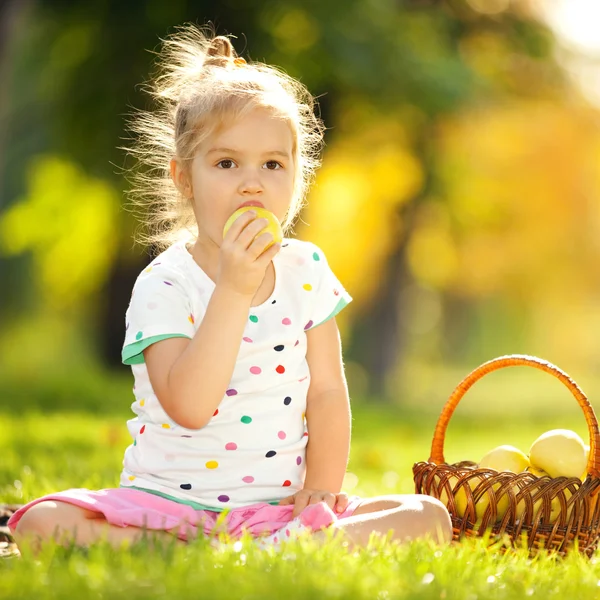 Süßes kleines Mädchen isst Apfel im Park — Stockfoto