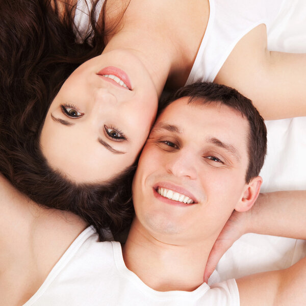 Молодая счастливая пара лежит в белой постели

