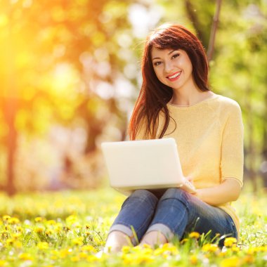 sevimli kadın karahindiba parkta beyaz dizüstü bilgisayar ile