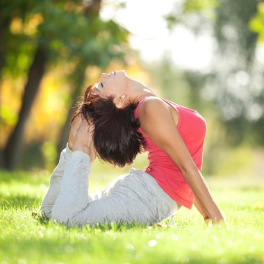 Parkta yoga egzersizi yapan güzel bir kadın.