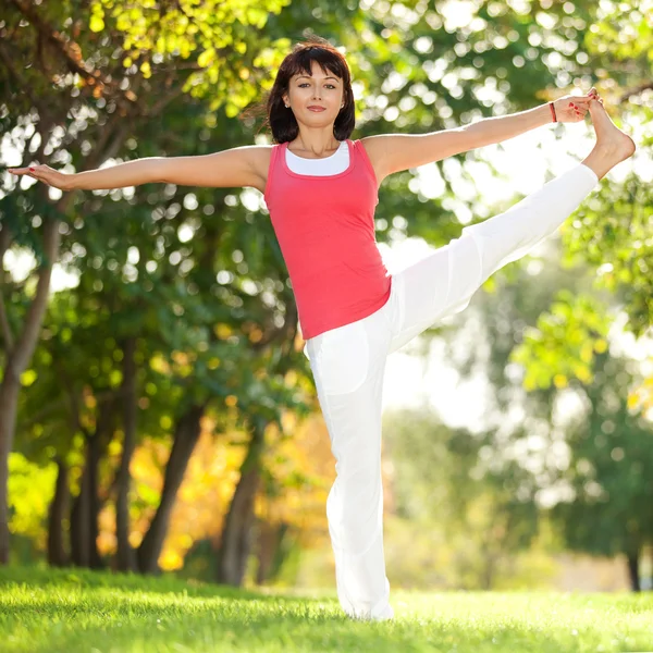 Parkta yoga egzersizi yapan güzel bir kadın. — Stok fotoğraf