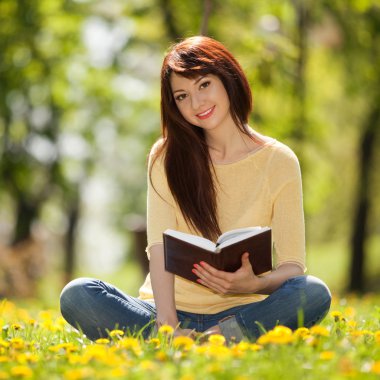 genç kadın çiçeklerle parkta bir kitap okuma