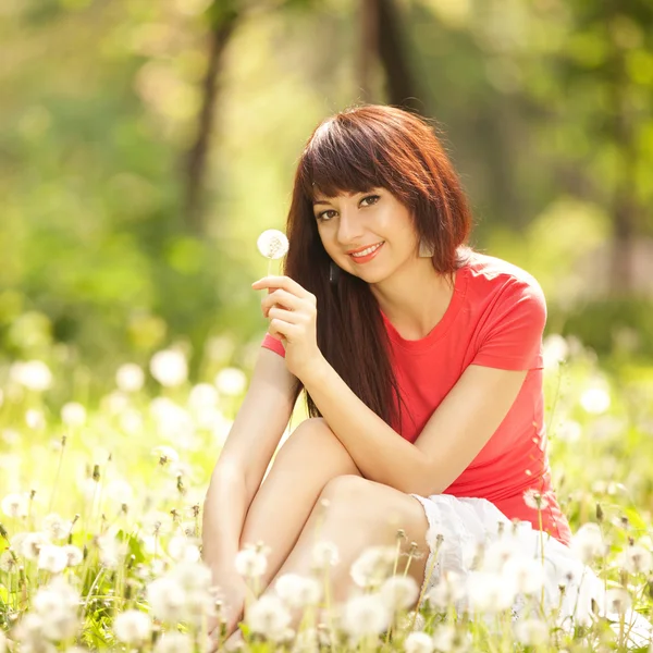 Leuke vrouw in het park met paardebloemen — Stockfoto