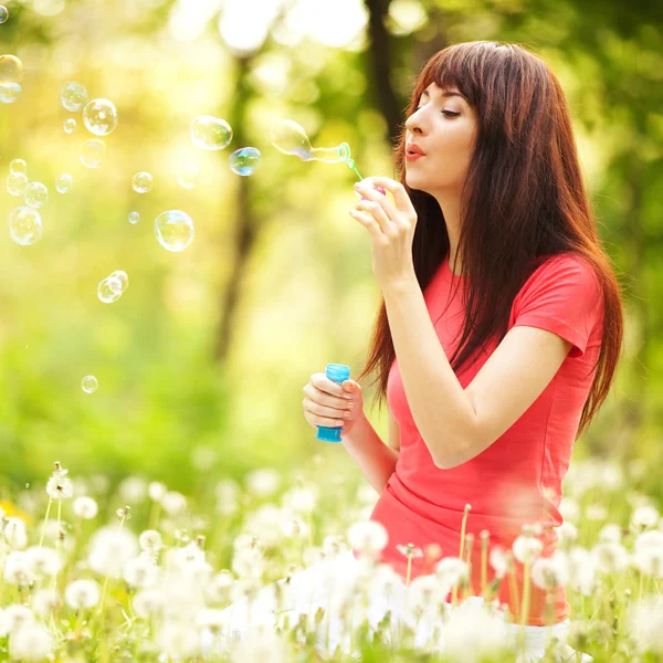 Happy woman blowing bubbles in the park — Stock Photo, Image