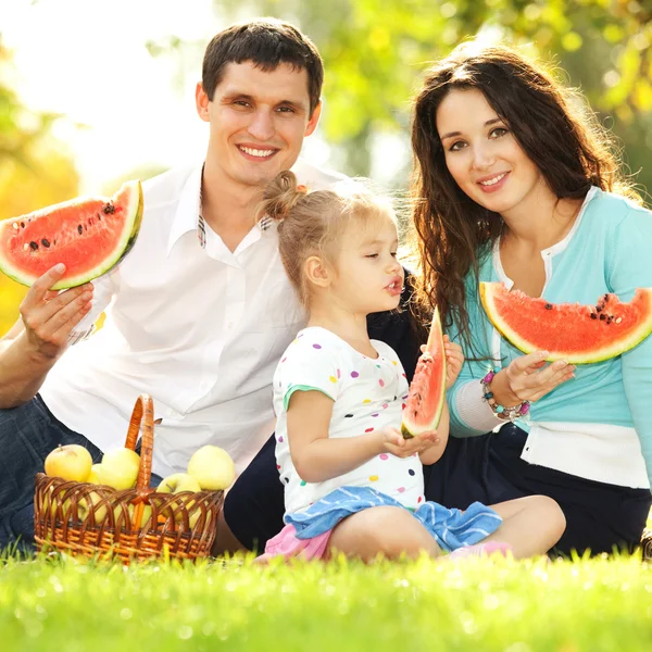 Família feliz fazendo um piquenique no jardim verde — Fotografia de Stock