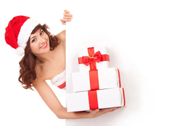 Santa mujer con cajas de regalo mirando el tablero blanco en blanco Imagen De Stock