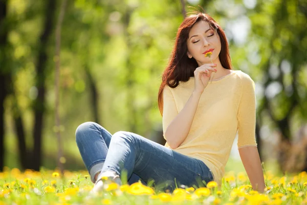 Junge rothaarige Frau im Park mit Blumen — Stockfoto