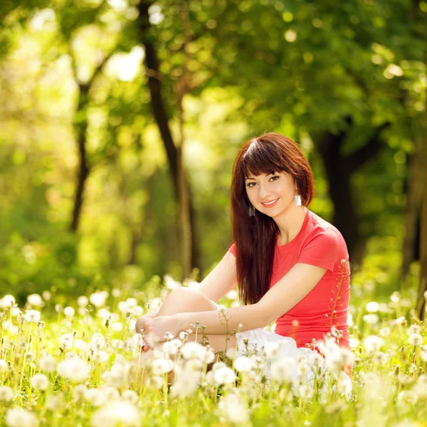Cute woman in the park with dandelions — Stock Photo, Image