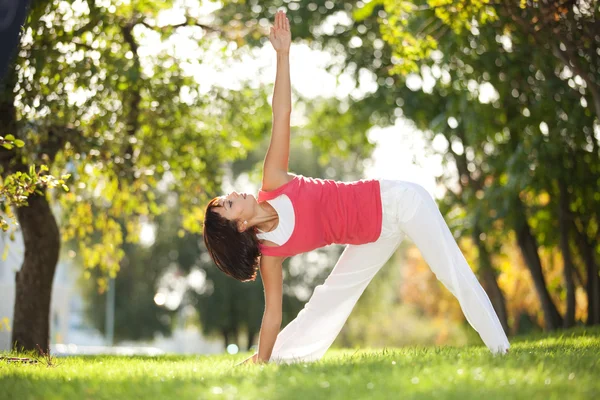 Hübsche Frau macht Yoga-Übungen im Park Stockfoto