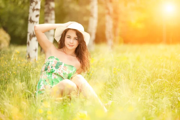 Jeune rousse femme dans le parc avec des fleurs — Photo