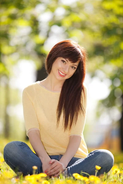 Junge glückliche Frau im Park mit Blumen — Stockfoto