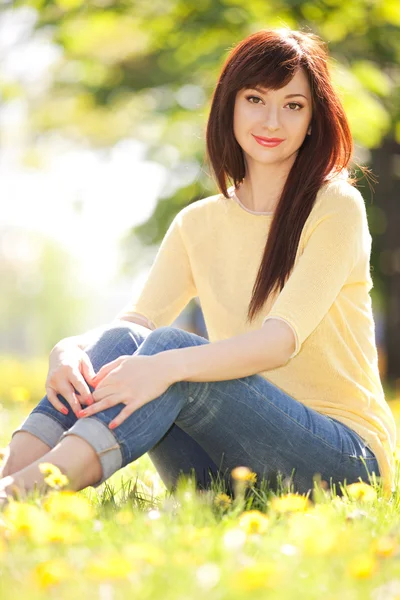 Young woman in the park with flowers — Stock Photo, Image