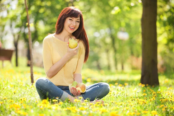 Glückliche Frau isst Früchte im Park — Stockfoto