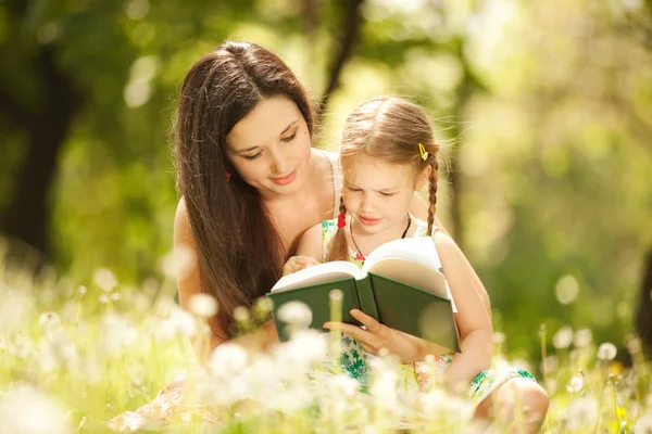 Mãe com filha ler um livro no parque — Fotografia de Stock