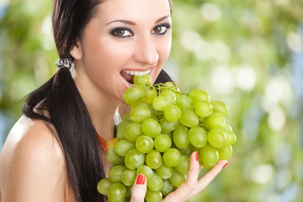 Красивая женщина с виноградом на зеленом фоне — стоковое фото