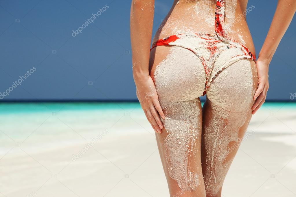 Sexy sandy woman buttocks on the beach background