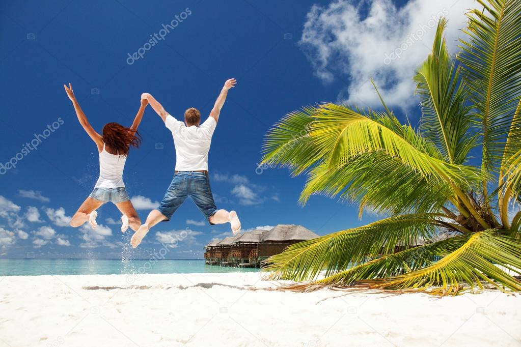 Happy couple jumping in the tropical beach