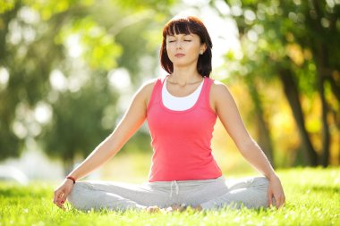 Parkta yoga egzersizi yapan güzel bir kadın.