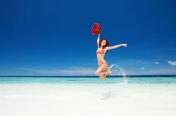 Szczęśliwa młoda kobieta skacząca po plaży — Zdjęcie stockowe