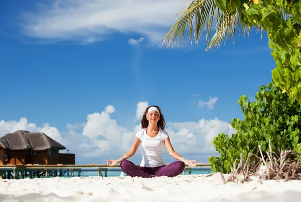 Pretty woman doing yoga exercises on the tropical beach — Stock Photo, Image
