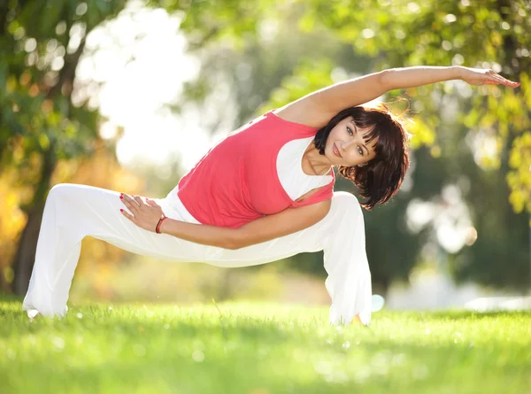 Hübsche Frau macht Yoga-Übungen im Park Stockbild
