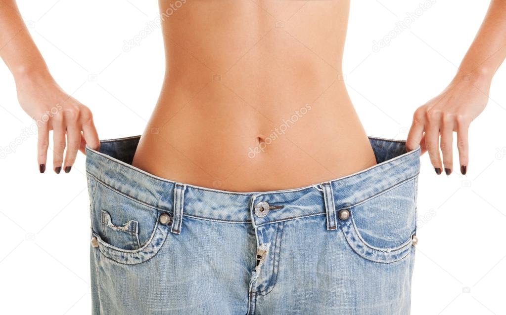 Woman shows her weight loss by wearing an old jeans, isolated on