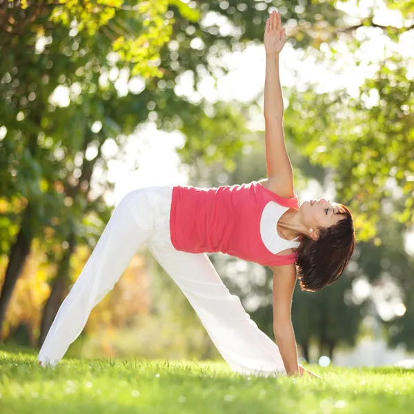 Bella donna che fa esercizi di yoga nel parco — Foto Stock