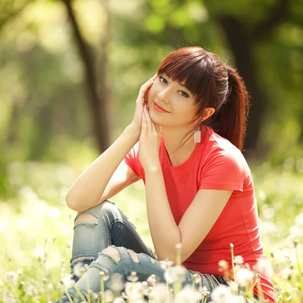 Mujer linda en el parque con dientes de león — Foto de Stock