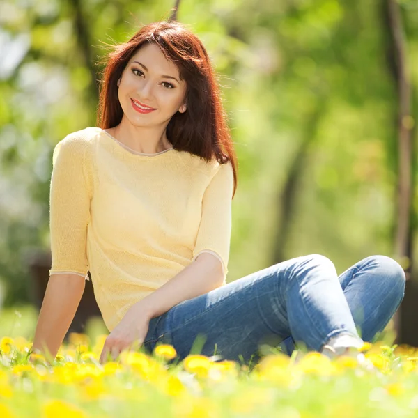 Gelukkig jongedame in het park met bloemen — Stockfoto