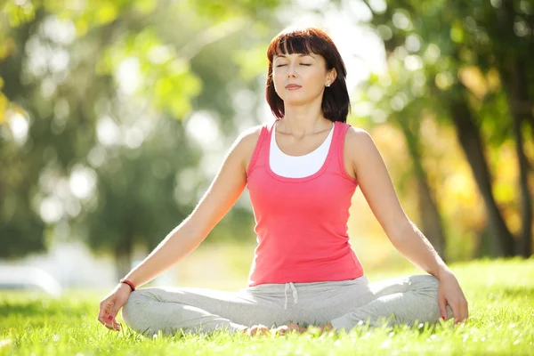 Parkta yoga egzersizi yapan güzel bir kadın. — Stok fotoğraf