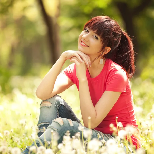 Leuke vrouw in het park met paardebloemen — Stockfoto