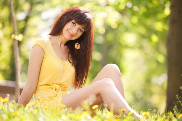 Joven mujer feliz en el parque con flores — Foto de Stock