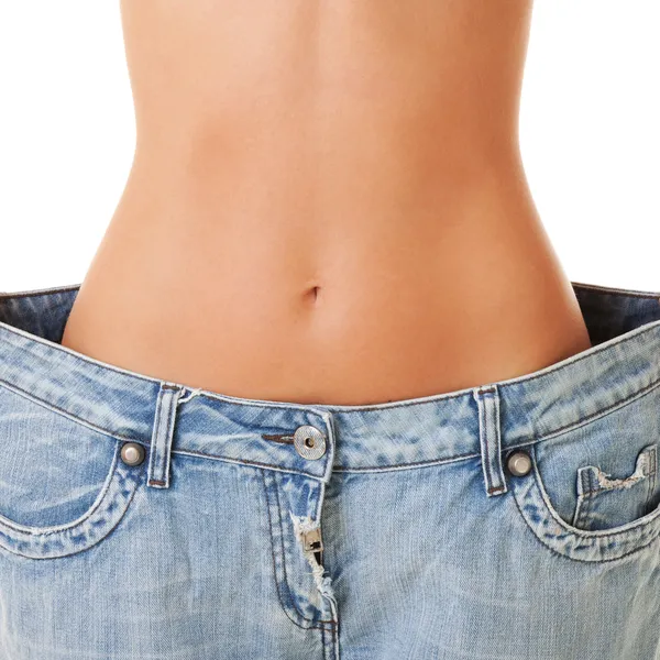 Женщина показывает свою потерю веса, надев старые джинсы, изолированные на Стоковое Изображение