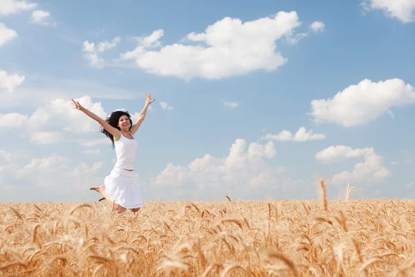 Happy woman jumping in golden wheat — Stock Photo, Image