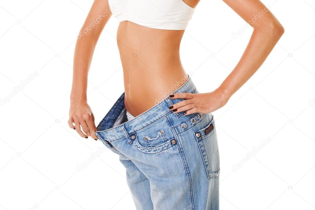 woman shows her weight loss by wearing an old jeans, isolated on