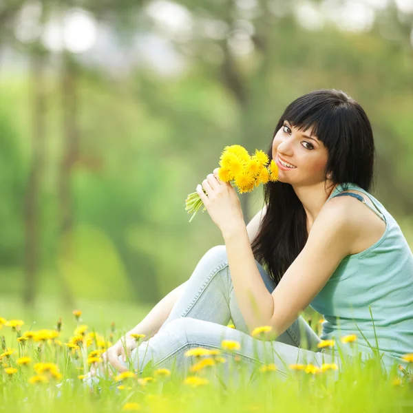 Leuke vrouw in het park met paardebloemen — Stockfoto