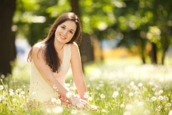 Leuke vrouw rust in het park met paardebloemen — Stockfoto