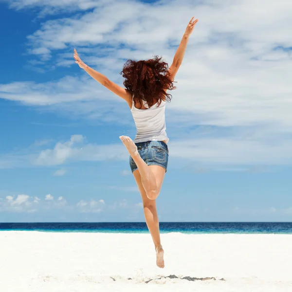Szczęśliwa młoda kobieta skacząca po plaży — Zdjęcie stockowe