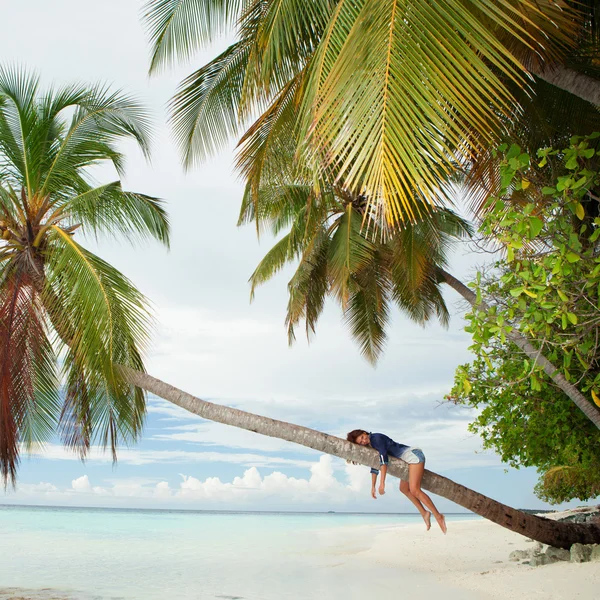 Mujer feliz acostada sobre una palmera en la playa —  Fotos de Stock