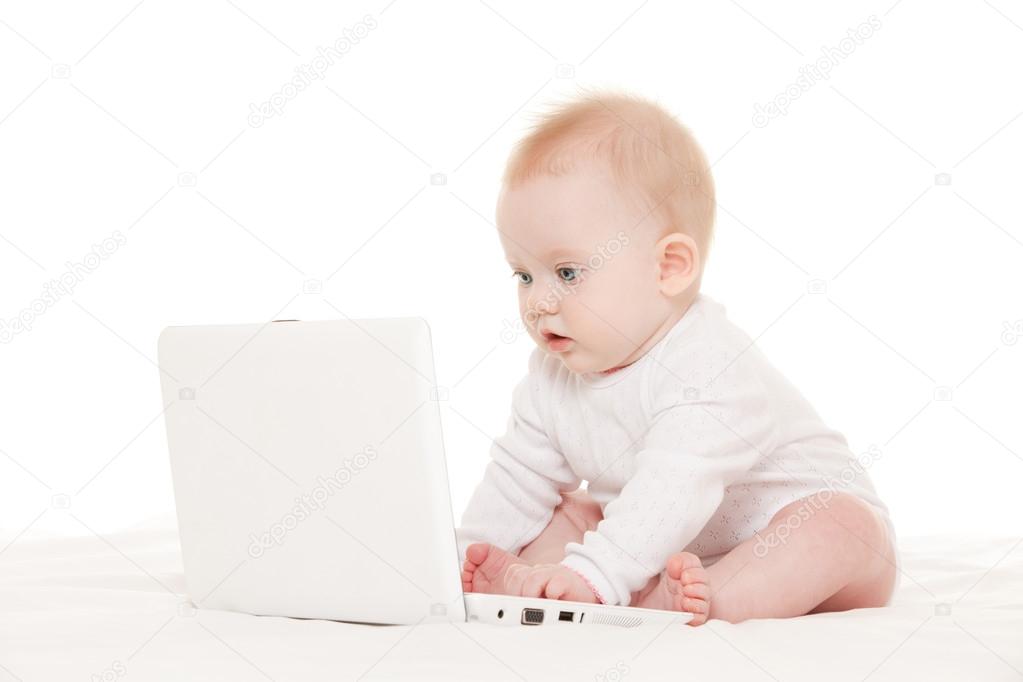 Cute baby with laptop on the white bed