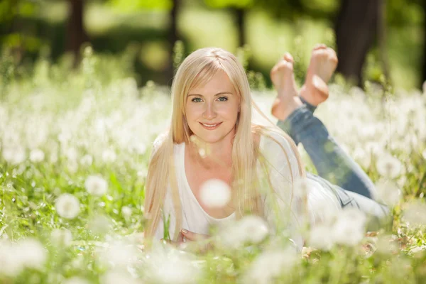 Femme mignonne dans le parc avec des pissenlits — Photo