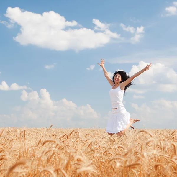 Happy woman jumping in golden wheat — Stock Photo, Image