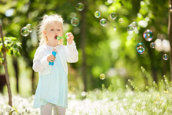 Cute dziewczynka dmuchanie baniek w parku — Zdjęcie stockowe