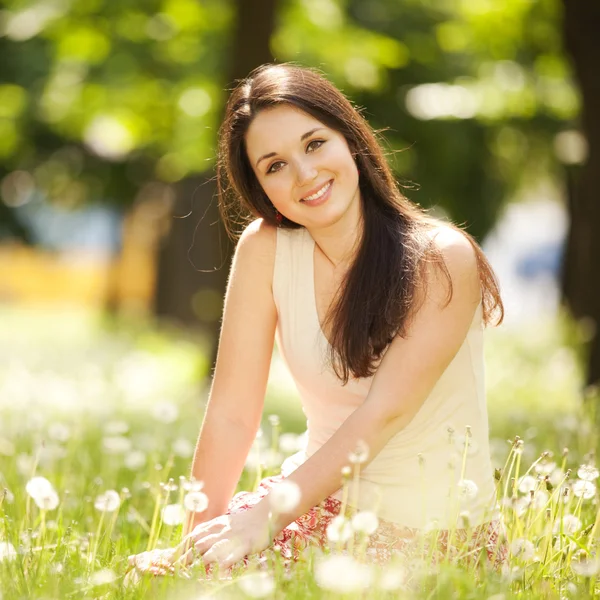 Cute woman rest in the park with dandelions — Stock Photo, Image