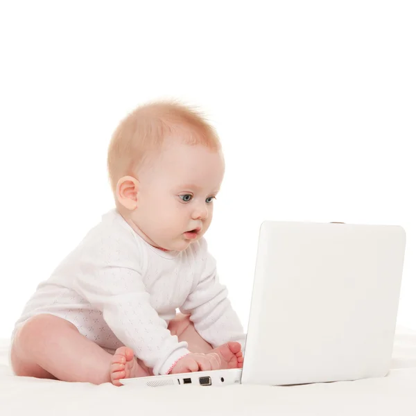 Cute baby with laptop on the white bed — Stock Photo, Image