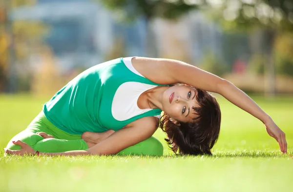 Parkta yoga egzersizi yapan güzel bir kadın. — Stok fotoğraf