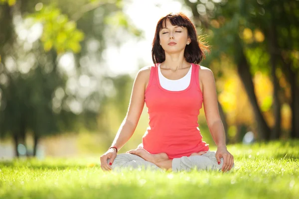 Parkta yoga egzersizi yapan güzel bir kadın. — Stok fotoğraf