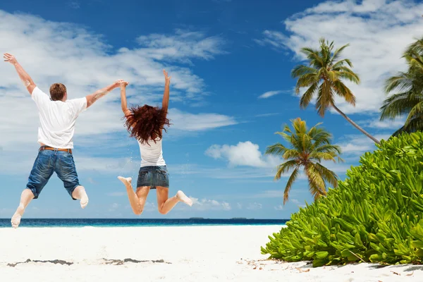 Happy couple jumping on the tropical beach — Stock Photo, Image