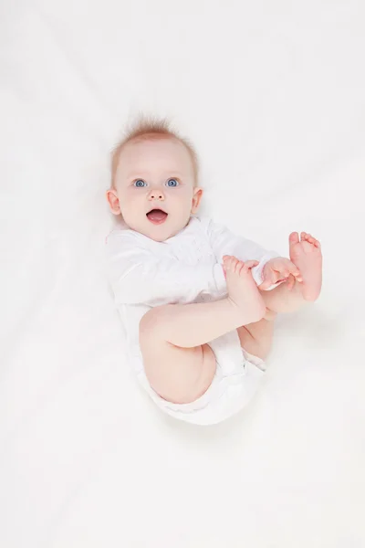 Lindo bebé con hermosos ojos azules acostado en la cama blanca — Foto de Stock