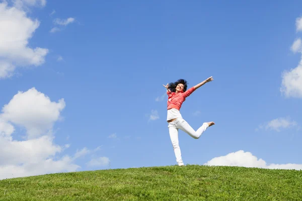 Mooie jonge vrouw springen op groen gras — Stockfoto